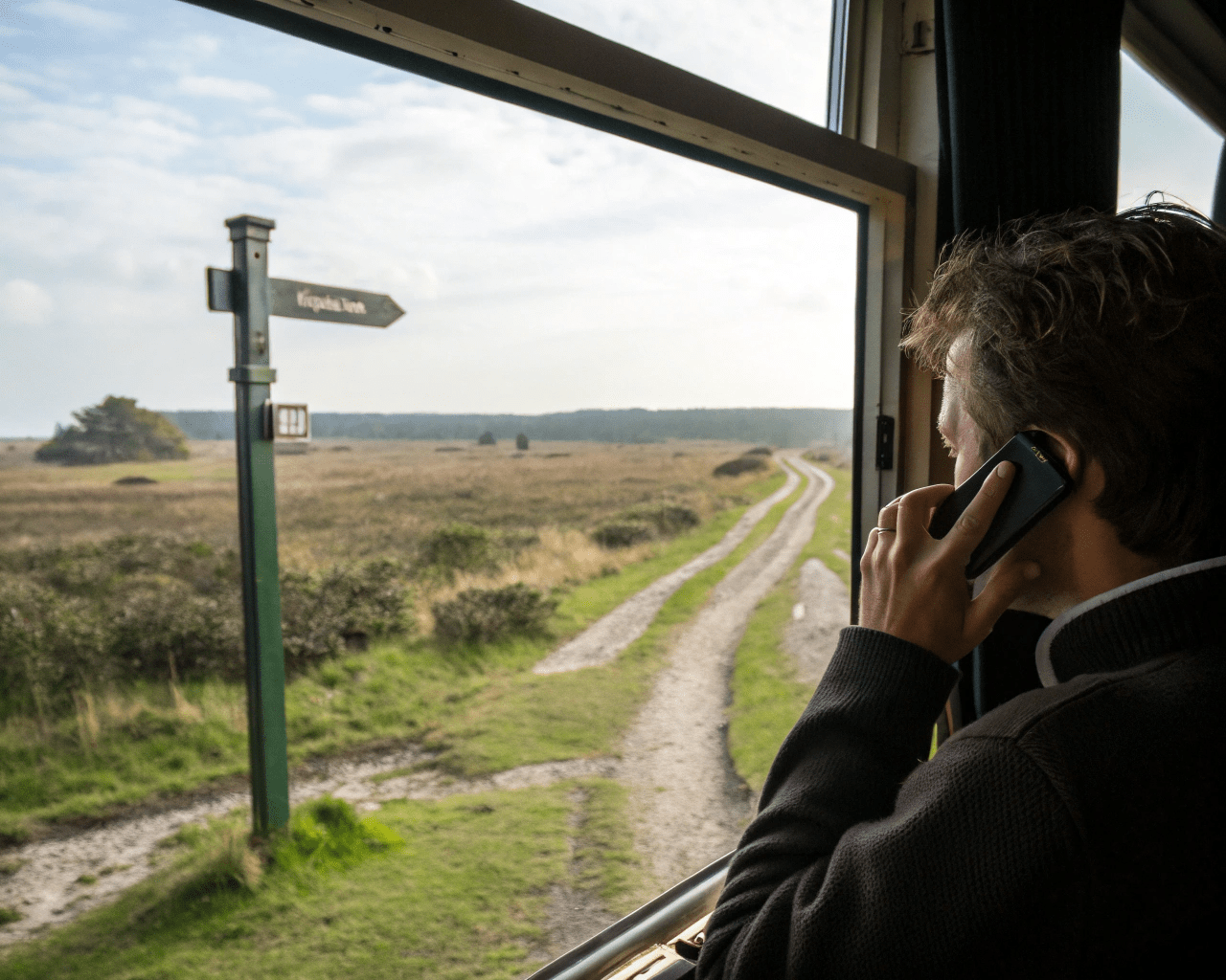 Phone-through-the-window a man sitting on a bus looking through the window and seeing a sign pointing the way emphasising unlock your potential