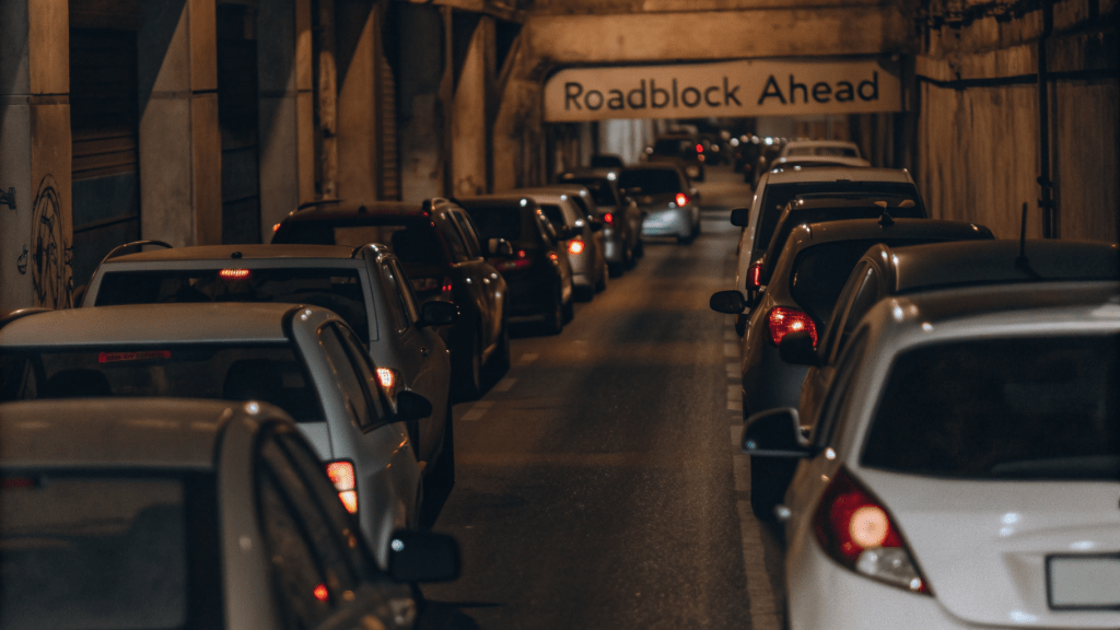 A traffic jam with a sign the reads “roadblock” in the distance