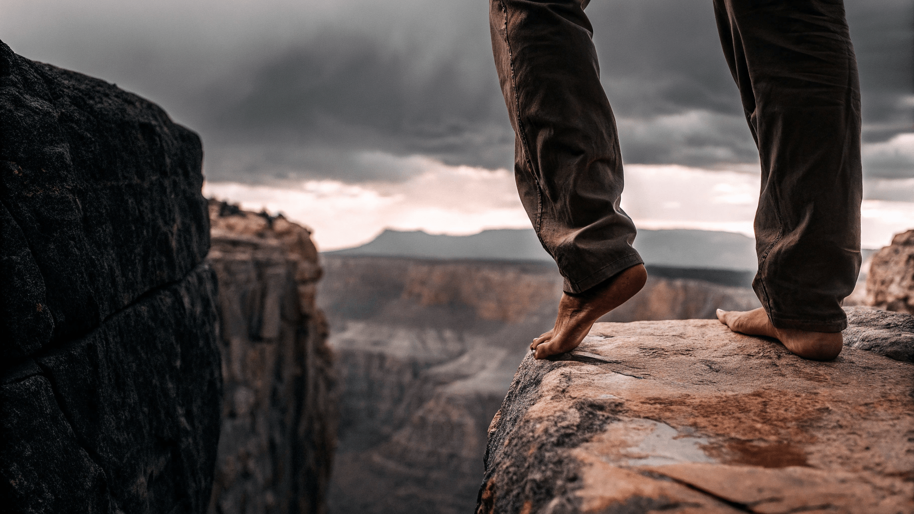a close up of someone's feet standing on the edge of a cliff hesitating to jump