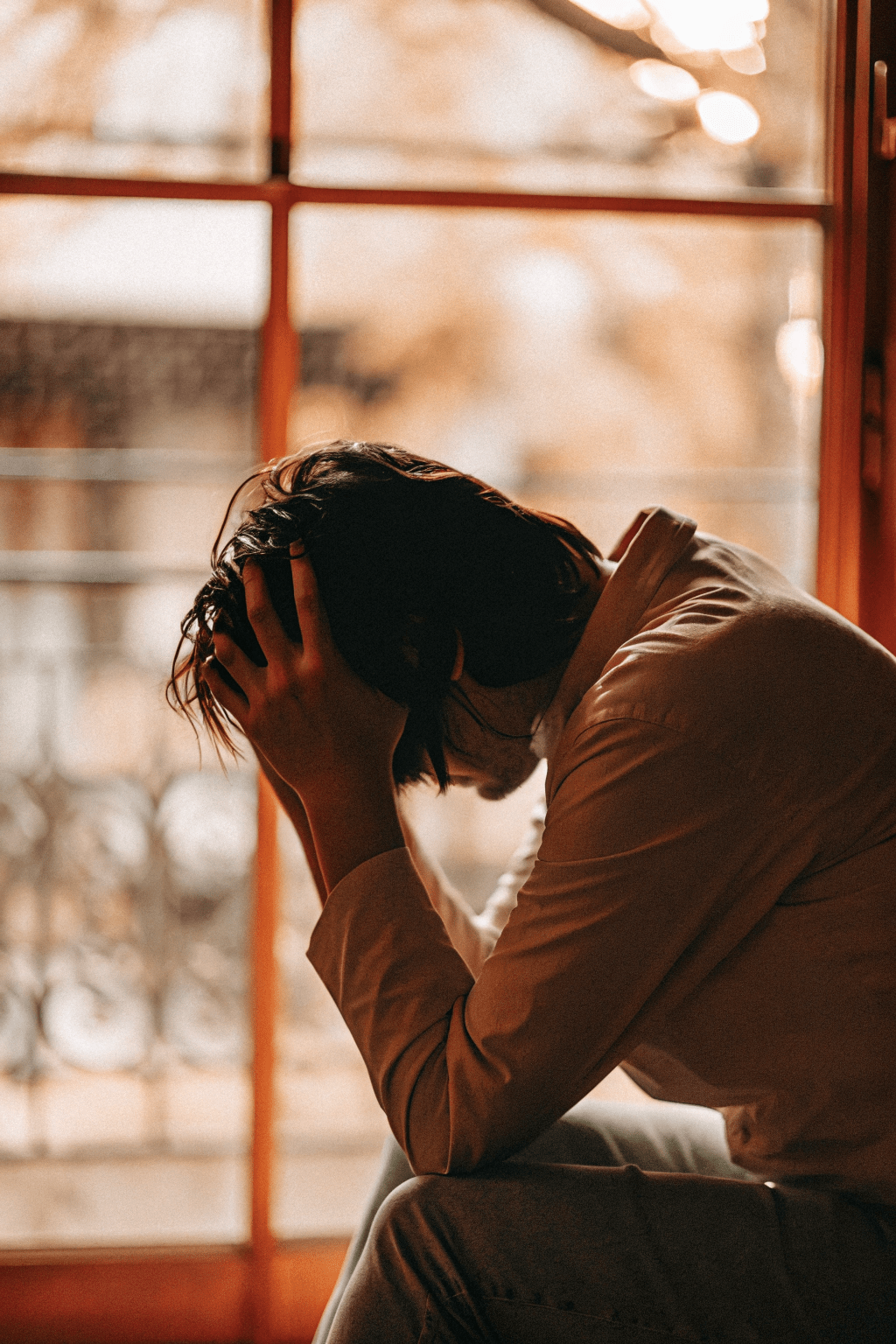 head-in-hands the emotional impact of someone experiencing burnout from imposter syndrome. sat head in hands